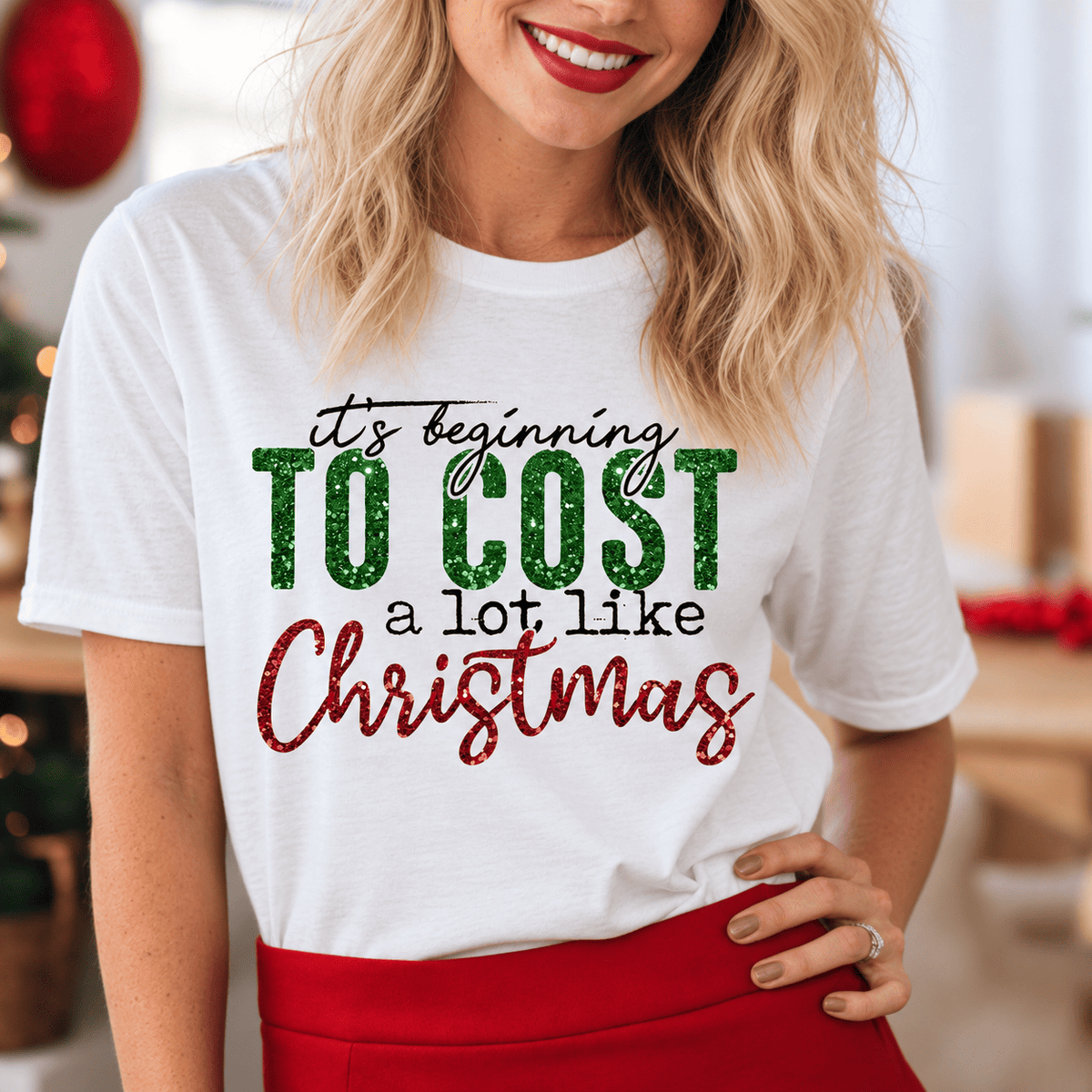 Digital mockup: close-up of green glitter TO COST and red glitter Christmas lettering on a white tee