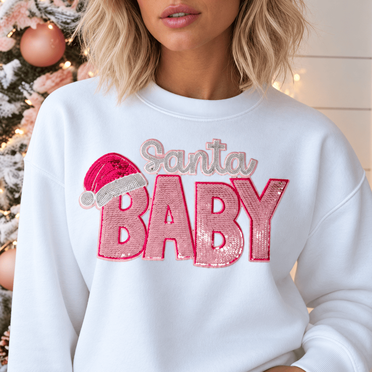 Digital mockup: close-up of the Santa Baby patch with a pink sequin hat and BABY lettering on a white crewneck